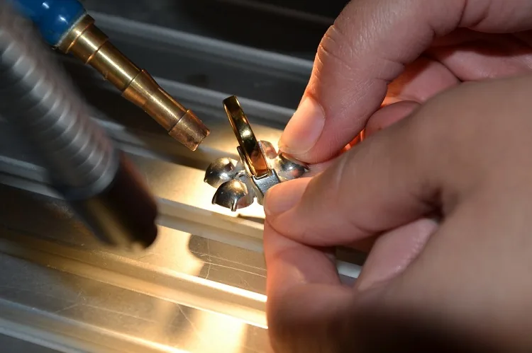 Wertschätzung – das Dankeschön von Sigma Laser an die Laserschweiß-Community, 17. November 2026 5 Zwei Hände führen ein kleines Goldteil unter dem Laserschweißkopf